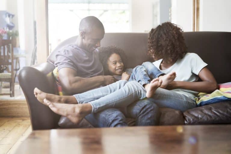 Happy parents are playing with son in living room.