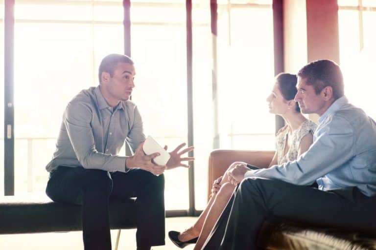 Confident businessman talking to couple.